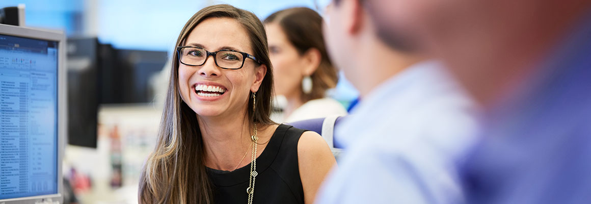 female employee at desk smiling and engaging with colleagues